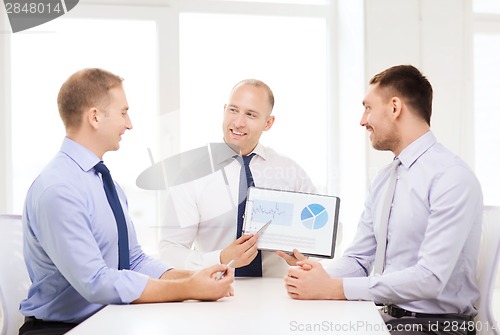 Image of smiling businessmen with papers in office