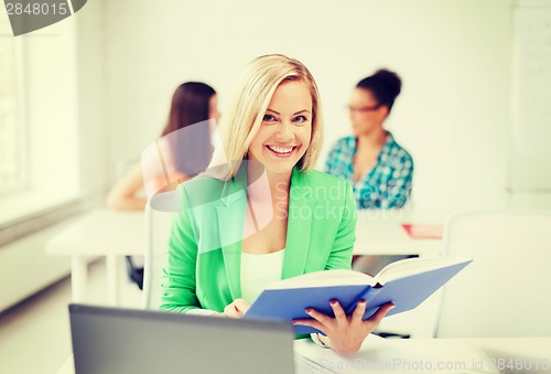 Image of smiling young girl reading book at school