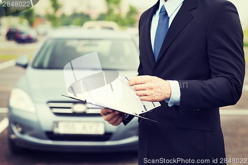 Image of man with car documents outside