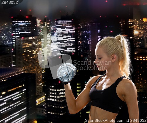 Image of young sporty woman with heavy steel dumbbell