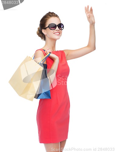 Image of smiling elegant woman in dress with shopping bags