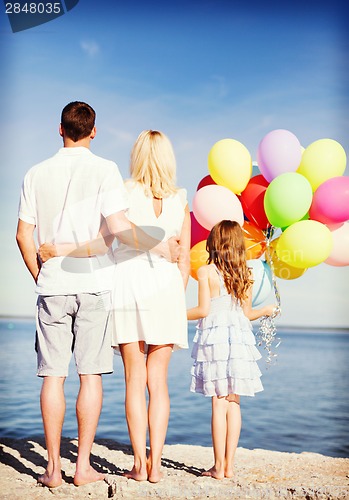 Image of happy family at the seaside with bunch of balloons
