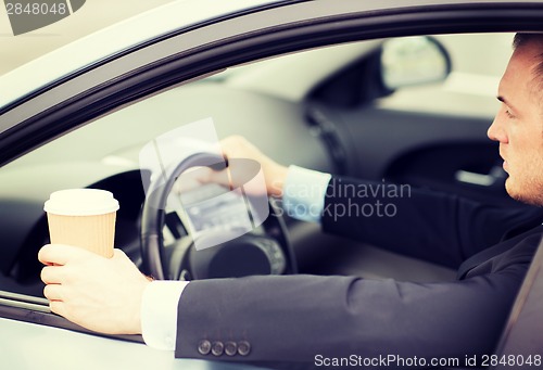 Image of man drinking coffee while driving the car