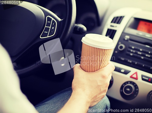 Image of man drinking coffee while driving the car