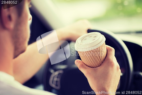 Image of man drinking coffee while driving the car