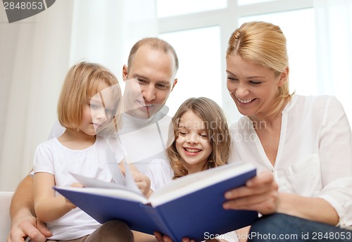 Image of smiling family and two little girls with book