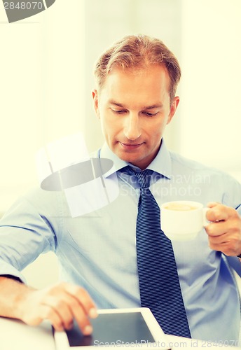 Image of businessman with tablet pc and coffee in office