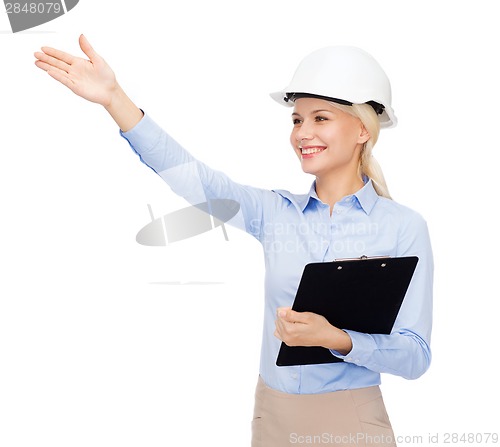 Image of smiling businesswoman in helmet with clipboard