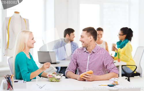 Image of smiling fashion designers having lunch at office