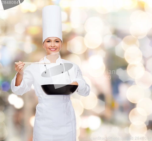 Image of smiling female chef with pan and spoon