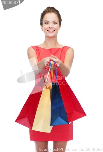 Image of smiling elegant woman in dress with shopping bags