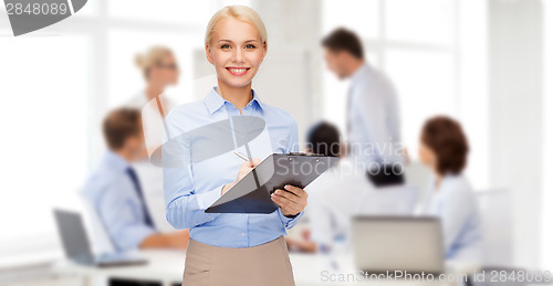 Image of smiling businesswoman with clipboard and pen