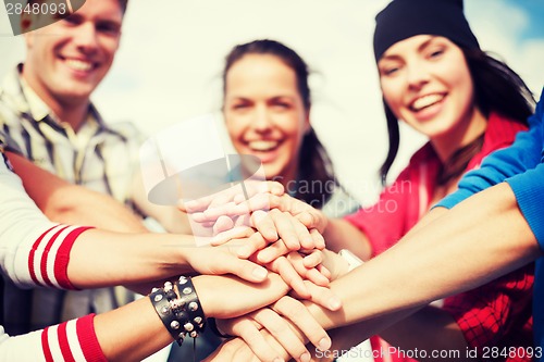 Image of teenagers hands on top of each other outdoors