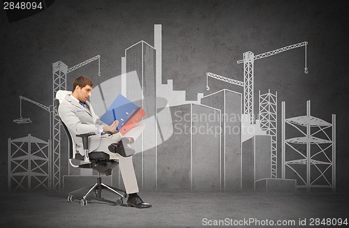 Image of handsome businessman with folders sitting on chair