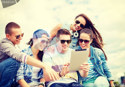 Image of group of smiling teenagers looking at tablet pc