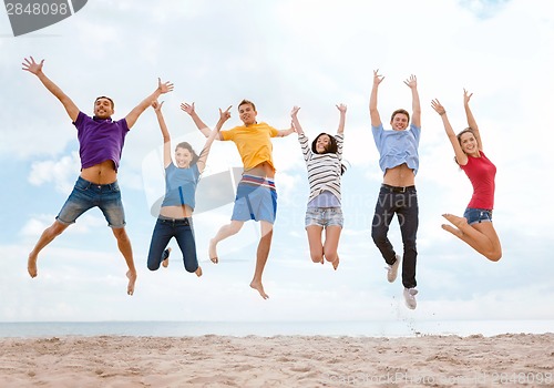Image of group of friends jumping on the beach