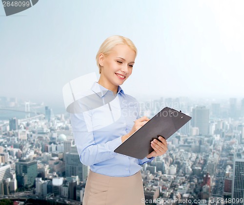 Image of smiling businesswoman with clipboard and pen