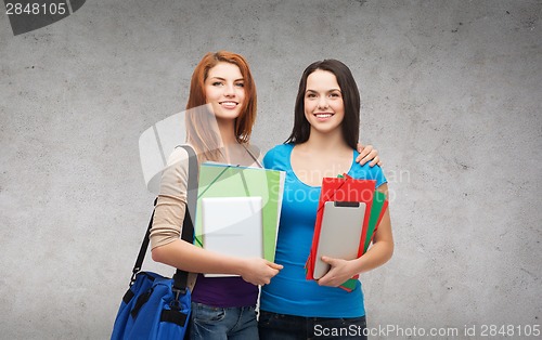 Image of two smiling students with bag, folders and tablet