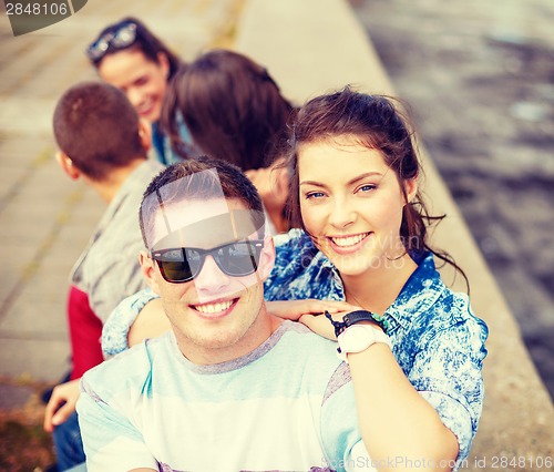 Image of smiling teenagers in sunglasses having fun outside