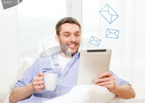 Image of smiling man working with tablet pc at home