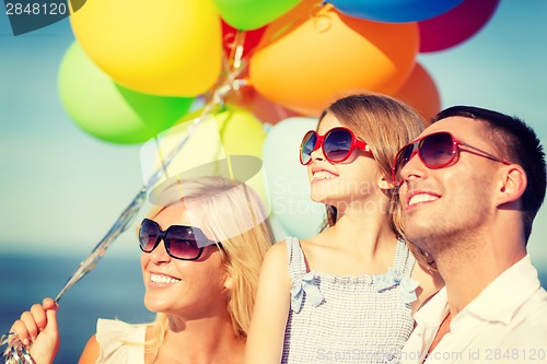 Image of happy family with colorful balloons outdoors