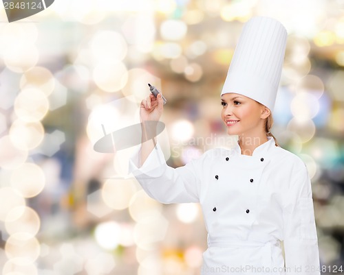 Image of smiling female chef writing something on air