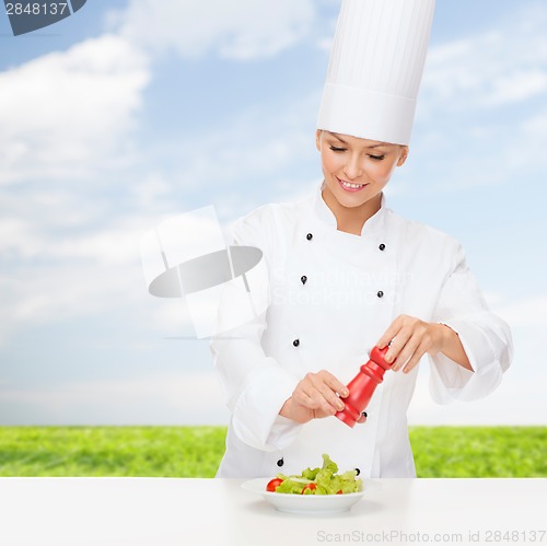 Image of smiling female chef with preparing salad