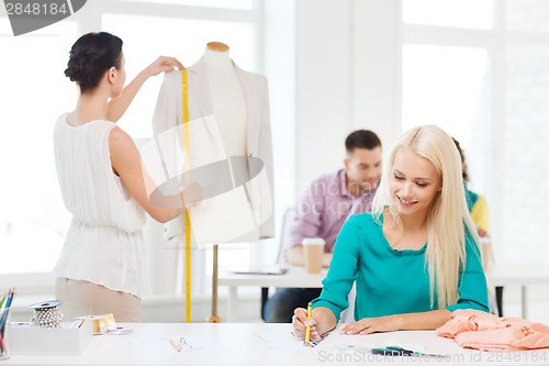 Image of smiling fashion designers working in office