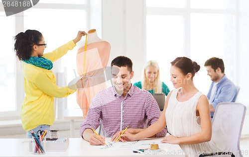 Image of smiling fashion designers working in office