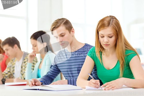 Image of tired students with textbooks and books at school