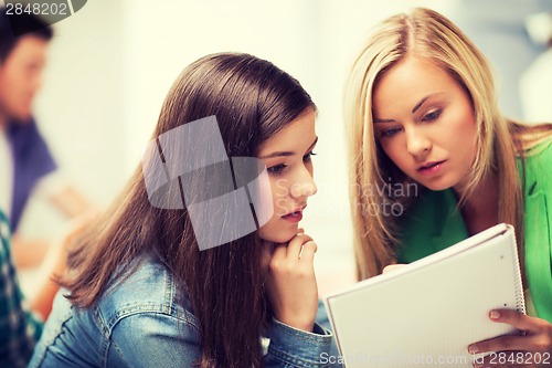 Image of student girls looking at notebook at school