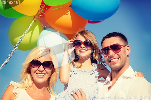 Image of happy family with colorful balloons outdoors