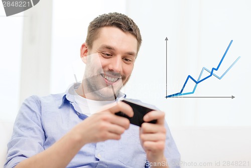 Image of smiling man with smartphone at home