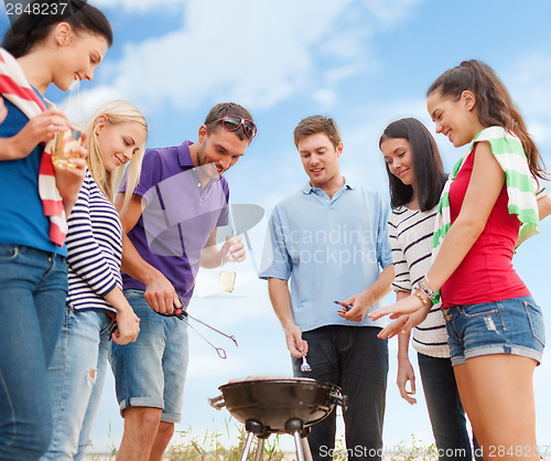 Image of group of friends making barbecue on the beach