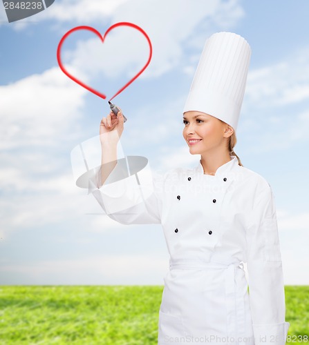 Image of smiling female chef drawing red heart on air