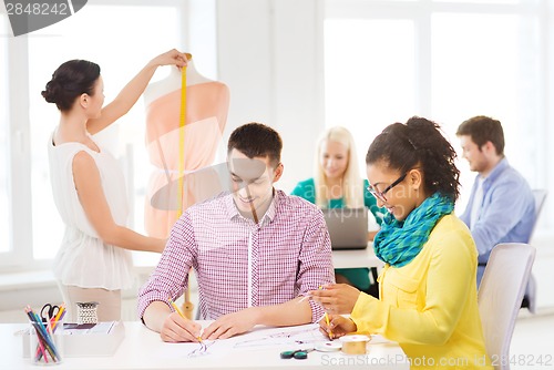 Image of smiling fashion designers working in office