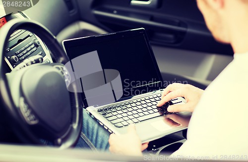 Image of man using laptop computer in car