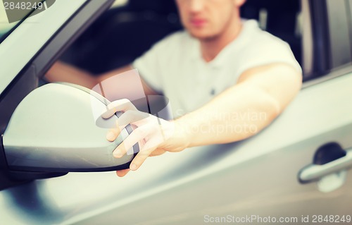 Image of man ajusting rear view mirror