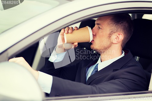 Image of man drinking coffee while driving the car