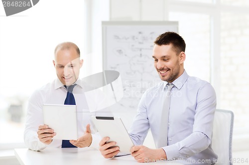 Image of two smiling businessmen with tablet pc in office