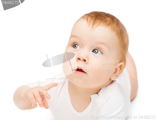 Image of curious baby lying on floor and looking side