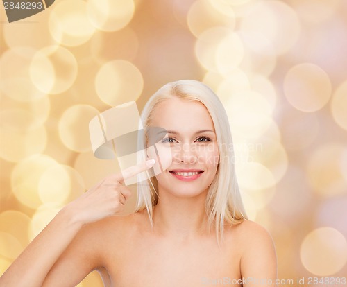 Image of smiling young woman pointing at her cheek