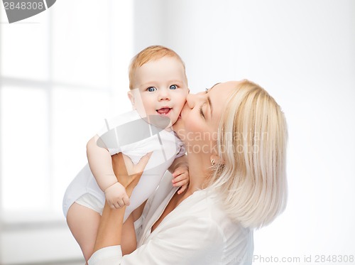 Image of happy mother kissing smiling baby