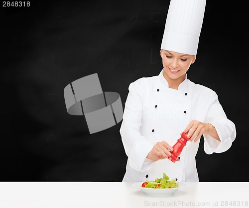 Image of smiling female chef with preparing salad