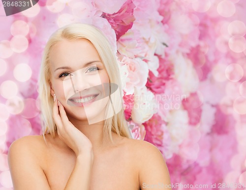 Image of smiling young woman touching her face skin
