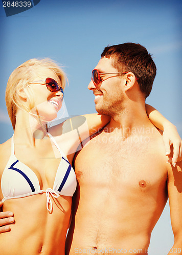 Image of happy couple in sunglasses on the beach