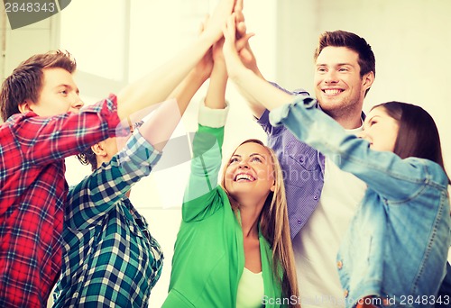 Image of happy students giving high five at school