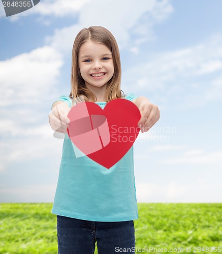 Image of smiling little girl giving red heart