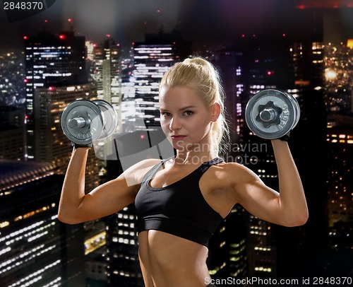 Image of sporty woman with heavy steel dumbbells