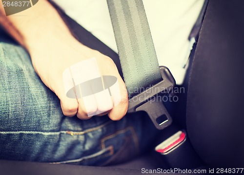 Image of man fastening seat belt in car